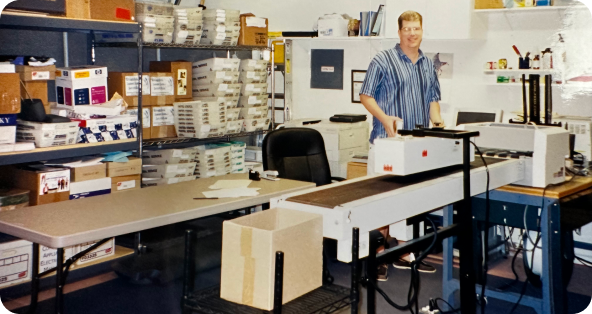 A man standing at a desk in a room full of boxes.