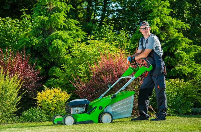 Landscaper facing the camera while holding the lawn mower