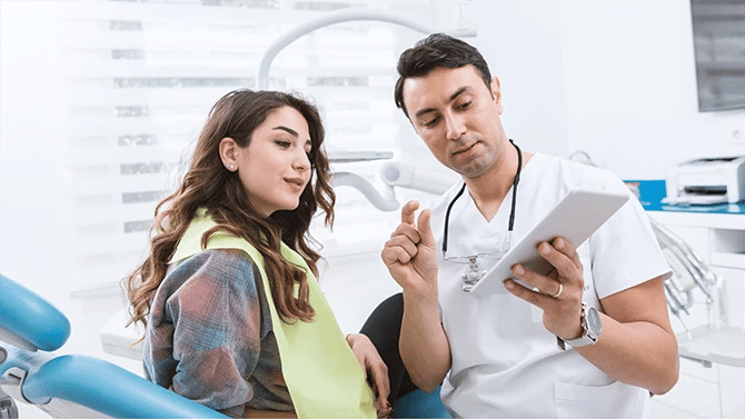 Dentist explaining procedure to a patient sitting on the dental chair