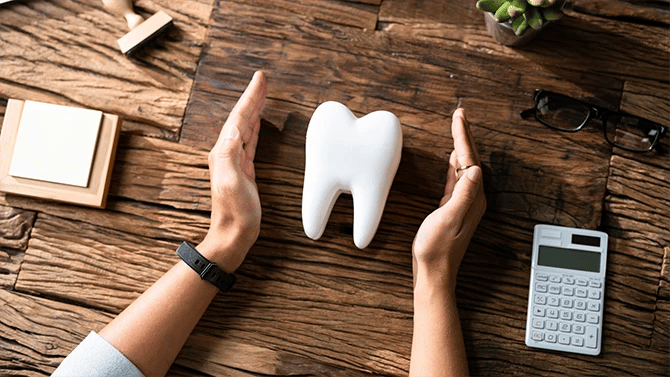 Two hands positioned like a barrier on either sides of a large tooth.