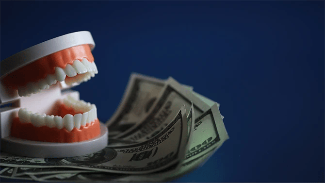 Dental teeth model on top of dollars.