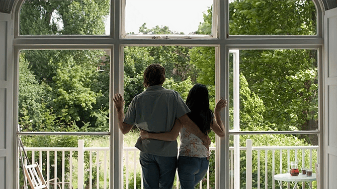 Couple hugging on a balcony while looking at their backyard 