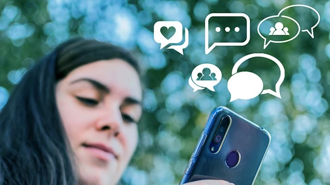 Close-up of a mobile phone with a female face and chat icons in the background