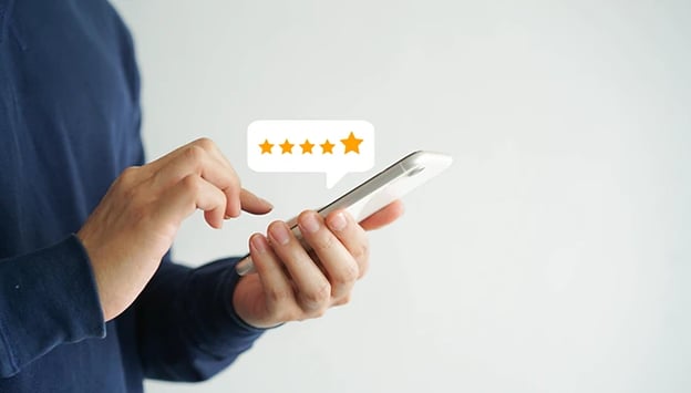 Close up on customer’s hand pressing on a smartphone screen with five star rating feedback icon