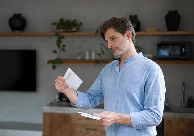 Portrait of a man at home checking letters in the mail and smiling.