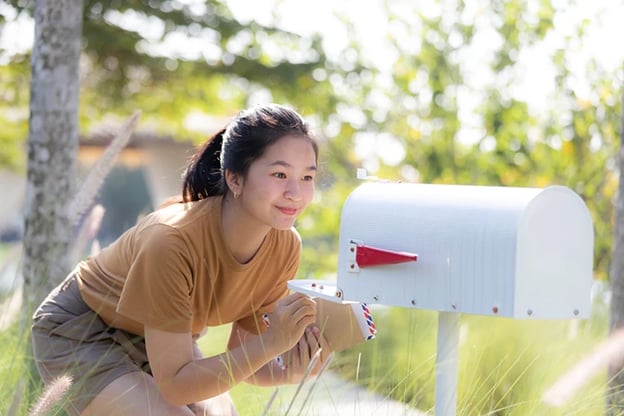 Woman looking inside her mailbox checking for a marketing campaign.