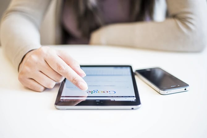 Close up image of fingers scrolling through Google website on a tablet