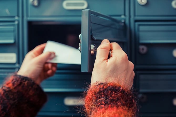 Close-up photo of a person unlocking a mailbox to get mail out