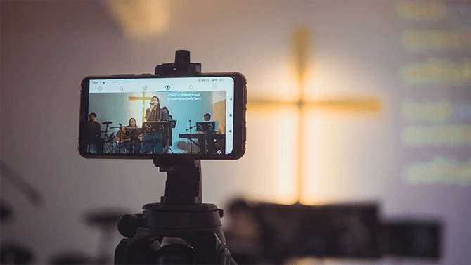 A mobile phone on a tripod streaming church worship service