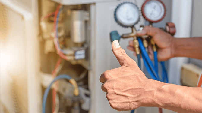 Man’s hand gesturing a thumbs up after completing an HVAC repair as shown in the background