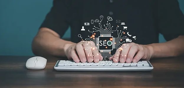 A person typing on a keyboard underneath a graphic of the word SEO within some circuitry