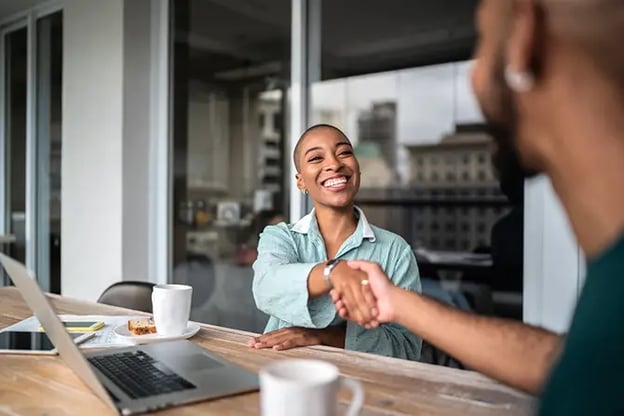 Two people sitting at a table and shaking hands
