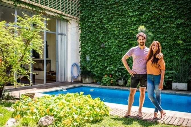 Happy young couple standing in the yard with a swimming pool