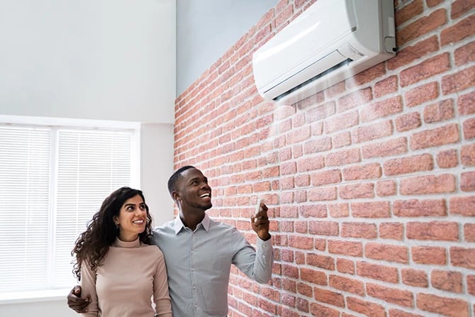 Image of a happy couple holding an air conditioner remote