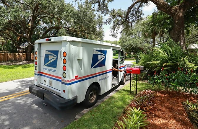United States Postal Service carrier delivers every door direct mail in a mailbox.