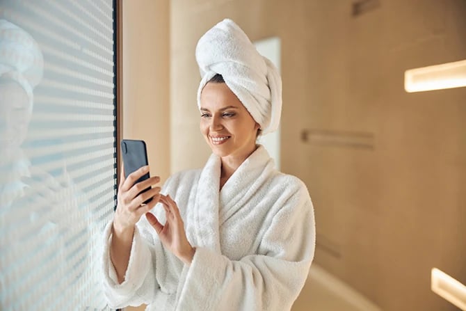 Waist-up portrait of a smiling woman at a day spa holding her mobile phone.