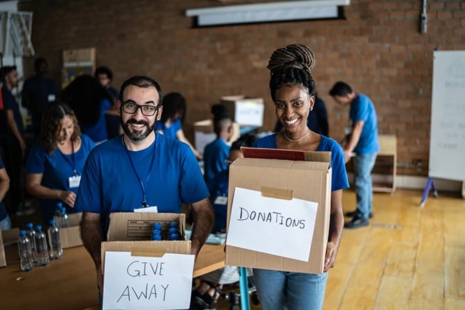 Portrait of volunteer church members who are holding charity boxes in a community center