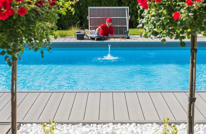 Professional pool company technician doing a check for a potential customer pool with a landscaped garden around.