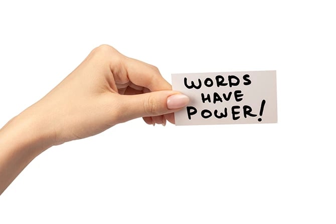 Words have power text on a card in a woman’s hand isolated on a white background.