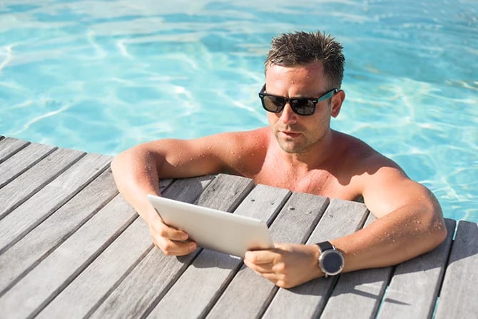 Man reading pool company marketing email on a digital tablet by the pool.