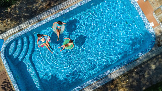 Aerial view of family in swimming pool. A happy mother and kids swim on inflatable ring.