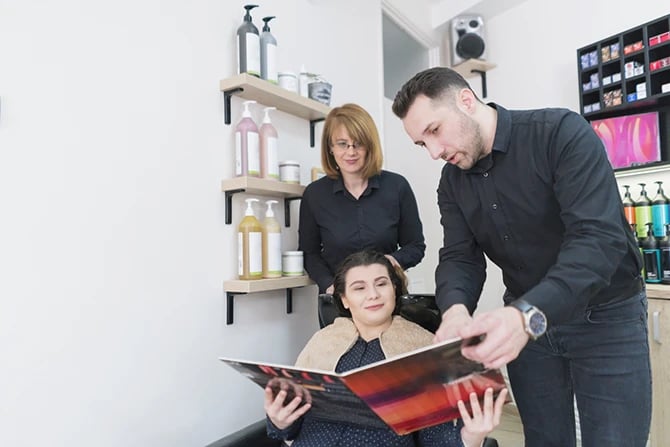 Hairdresser showing salon ads to a new client to choose the best color option.
