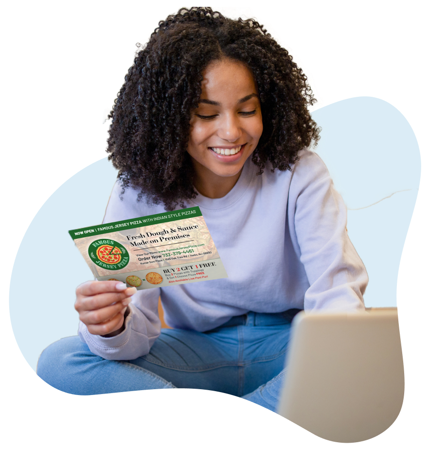 Woman_Looking_At_A_Laptop_And_Holding_An_EDDM_Postcard